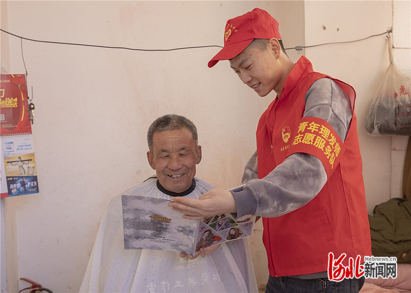 图2：在迁西县泰和里社区新蓝湾小区，青年理发师志愿者拿着剪发海报和老人一起挑选发型。.jpg