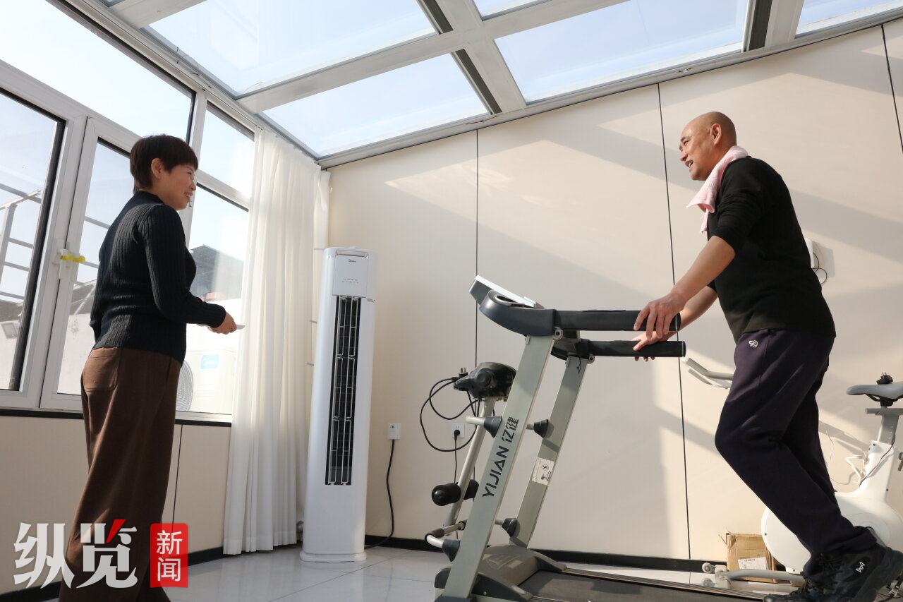 1月13日，滦南县倴城镇果园村村民钱玉凤（左）见正在跑步机上锻炼的丈夫出了不少汗，赶忙调低了空调温度。河北日报记者 王育民摄.JPG